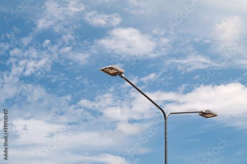 Streetlight with lamp pole against blue sky and clouds background.