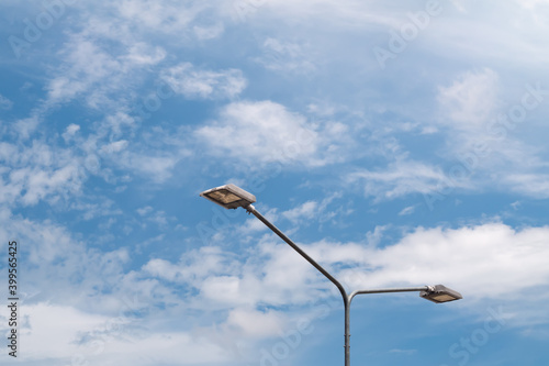 Streetlight with lamp pole against blue sky and clouds background.