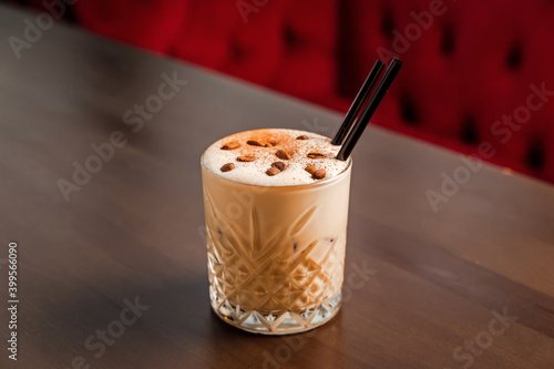 A creamy coffee alcoholic cocktail in a rocks, lowball, old fashioned glass, garnished with coffee beans photo