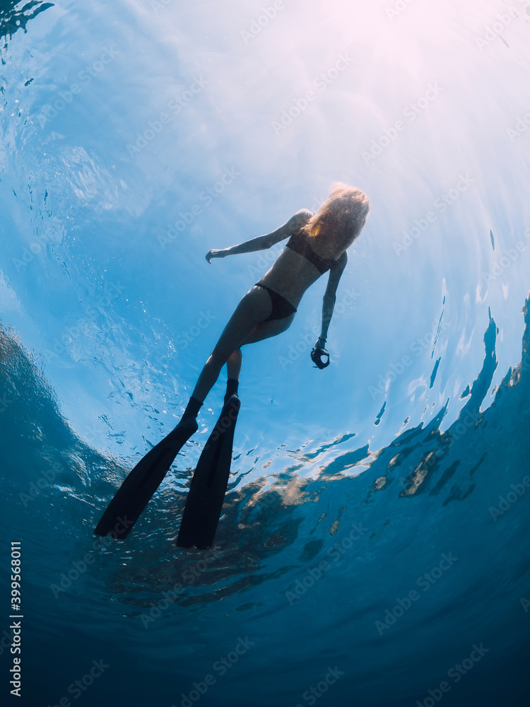 Woman freediver with fins relax on surface. Sport model in ocean