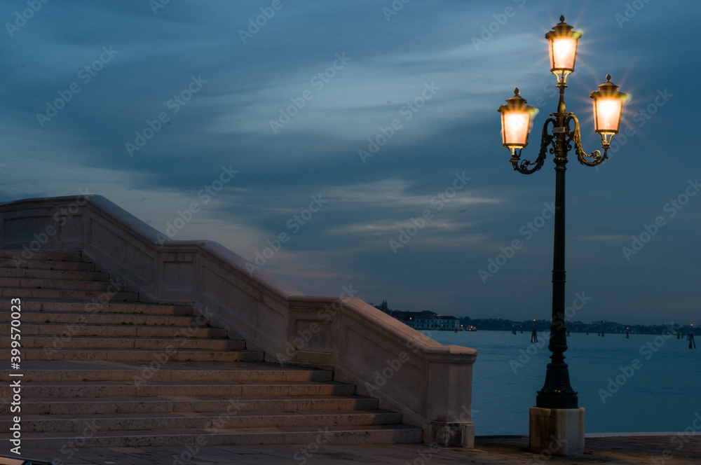 Handmade cast iron lamp in Venice during sunset light and the Venetian lagoon in the background