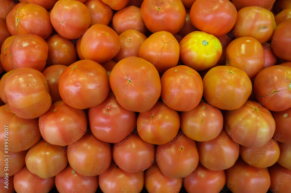 Pile of fresh ripe tomatoes in the Farmer's market, the very popular fruit of Solanum lycopersicum plant, generally prepared and consumed as a vegetable and used in various dishes and versatile sauces Pile of fresh ripe tomatoes in the Farmer's market, the very popular fruit of Solanum lycopersicum plant, generally prepared and consumed as a vegetable and used in various dishes and versatile sauces