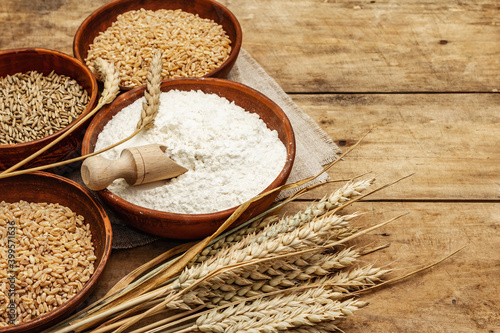 Ingredients for baking bread: wheat ears and a bowls of flour and grains
