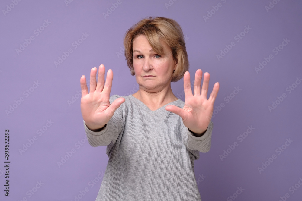 Middle age woman doing stop sing with palm of the hand. Warning expression with negative and serious gesture on the face. Middle age woman doing stop sing with palm of the hand. Warning expression with negative and serious gesture on the face.
