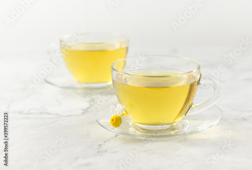 glass cups with chamomile tea on a light marble background.