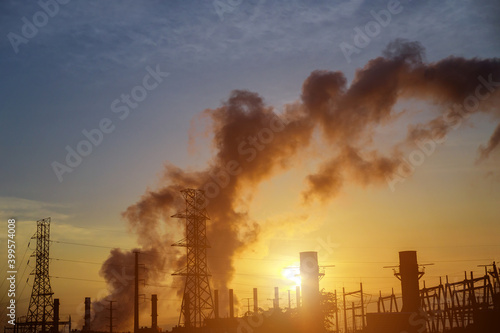 Gas turbine electrical power plant at dusk with during sunrise factory pipe polluting air.