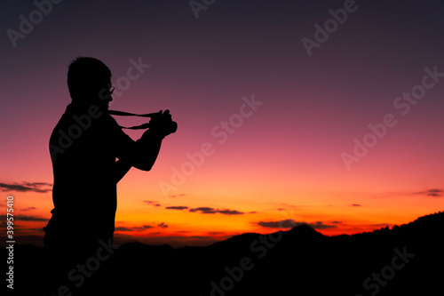 silhouette of man taking photo of sunrise from mountain