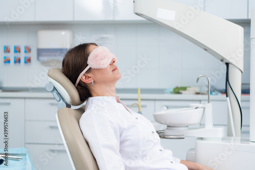 A doctor having a nap in the dental chair using a sleeping mask.