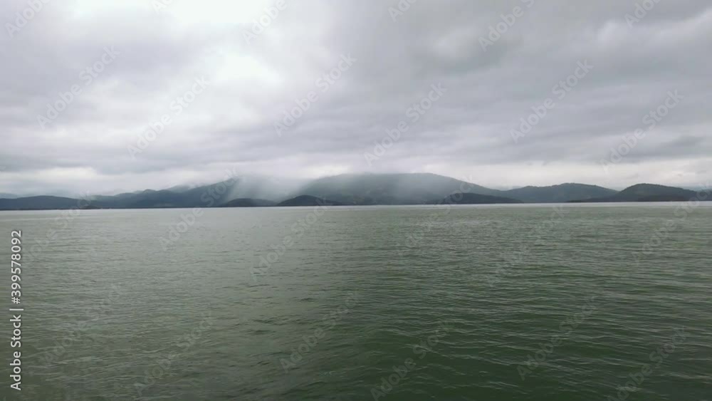 Moving boat at sea. Mountains with heavy rain forming in the background. Moving boat at sea. Mountains with heavy rain forming in the background.