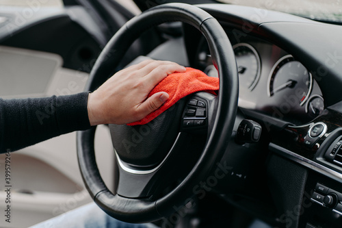 Close up shot of mans hand cleaning car steering wheel with microfiber cloth. Hygiene prevention during coronavirus outbreak © VK Studio
