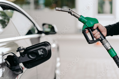 Fototapeta Cropped shot of mans hand pumping gasoline fuel in car at gas station