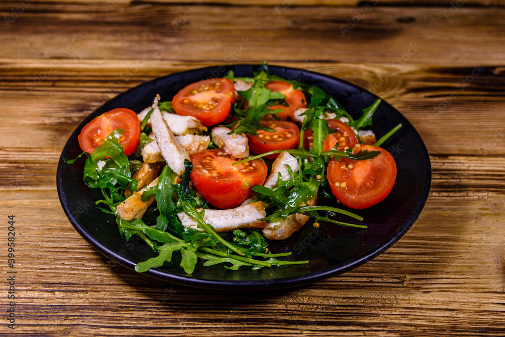 Roasted chicken breasts and salad with arugula and cherry tomatoes in a black plate Roasted chicken breasts and salad with arugula and cherry tomatoes in a black plate