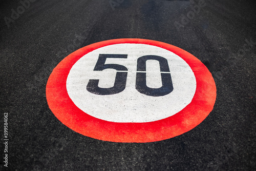 50km per hour speed limit sign painted on dark asphalting road. © Lalandrew