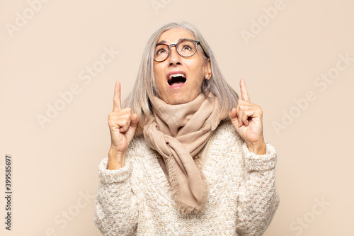 middle age woman feeling awed and open mouthed pointing upwards with a shocked and surprised look