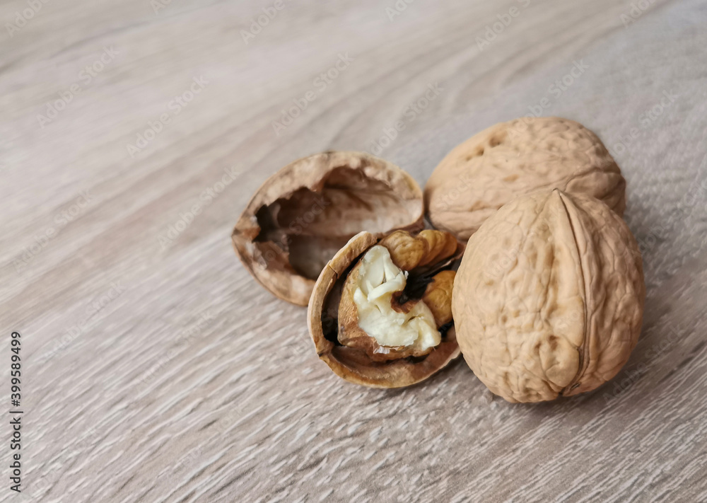 Two whole walnuts and one cracked walnut on a wooden table Two whole walnuts and one cracked walnut on a wooden table