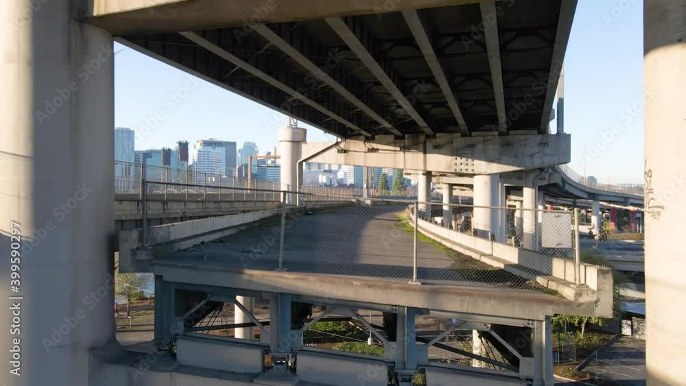 Drone flying just above the pedestrian overpass of multilevel bridge, adjacent to busy highway. Aerial.