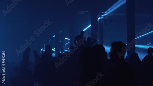 Big crowd of young people dancing at large music show event in nightclub photo