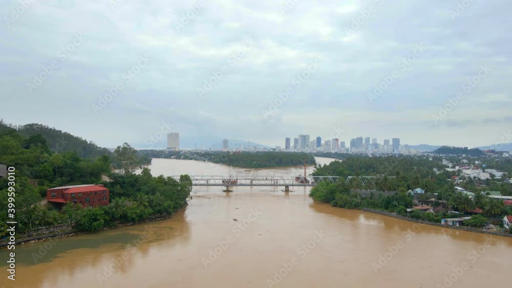 Aerial slow motion shot of a metal railway bridge over a river, which has a brownish-yellow color. Behind the bridge there is another one being constructed Aerial slow motion shot of a metal railway bridge over a river, which has a brownish-yellow color. Behind the bridge there is another one being constructed