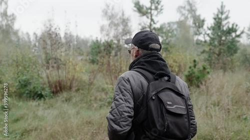 Wallpaper Mural rear view of a man in a cap and with a backpack walks through the woods, hiking in the woods Torontodigital.ca