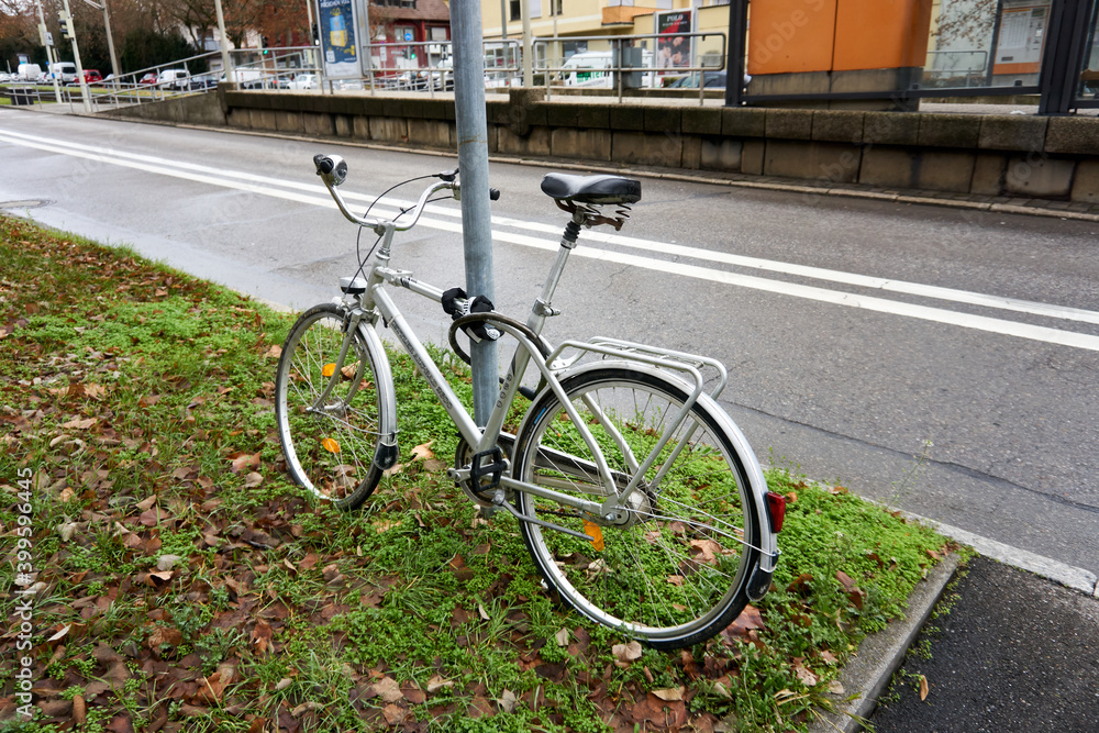A bycicle locked at a lantern next to the street and tram station