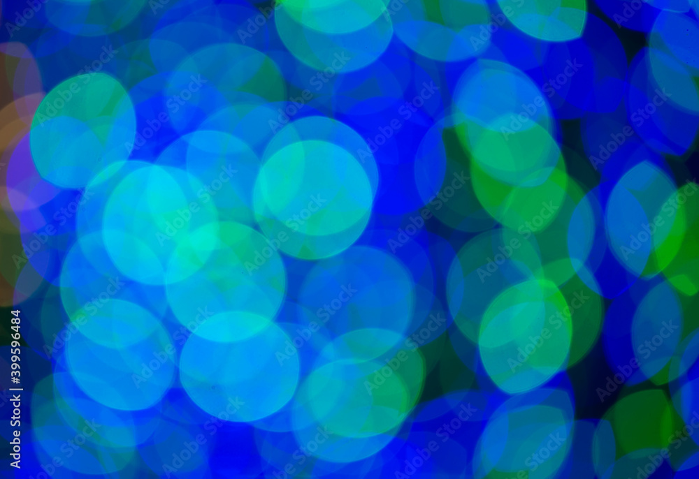 Multicolored large bokeh spots of blue, yellow and green. Bokeh from a Christmas garland. Multicolored large bokeh spots of blue, yellow and green. Bokeh from a Christmas garland.