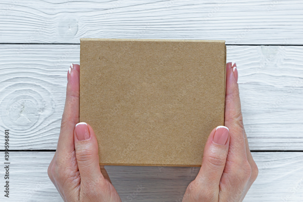 Female hands holding box on white wooden background. Mockup. Template Female hands holding box on white wooden background. Mockup. Template