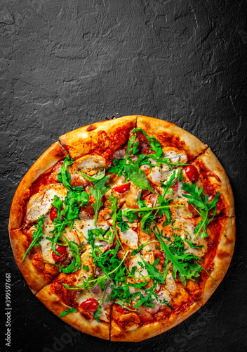 Pizza with chicken, bacon, cheese, tomato and arugula. Italian pizza on Dark grey black slate background