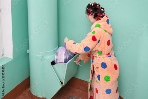 Foto housewife in a orange dressing gown with polka dots and curlers on her head thro