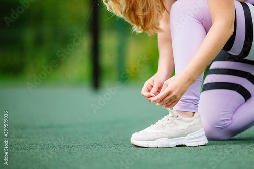 Cropped image of hands tying shoelaces of sneaker. Young woman runner tying shoelaces