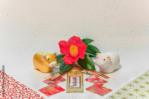 Japanese New Year's Card with handwriting ideograms Kingashinnen or Happy New Year on a traditional decoration with a Tsubaki flower and two Zodiacal animals figurines of cows for the Year of the Ox. photo