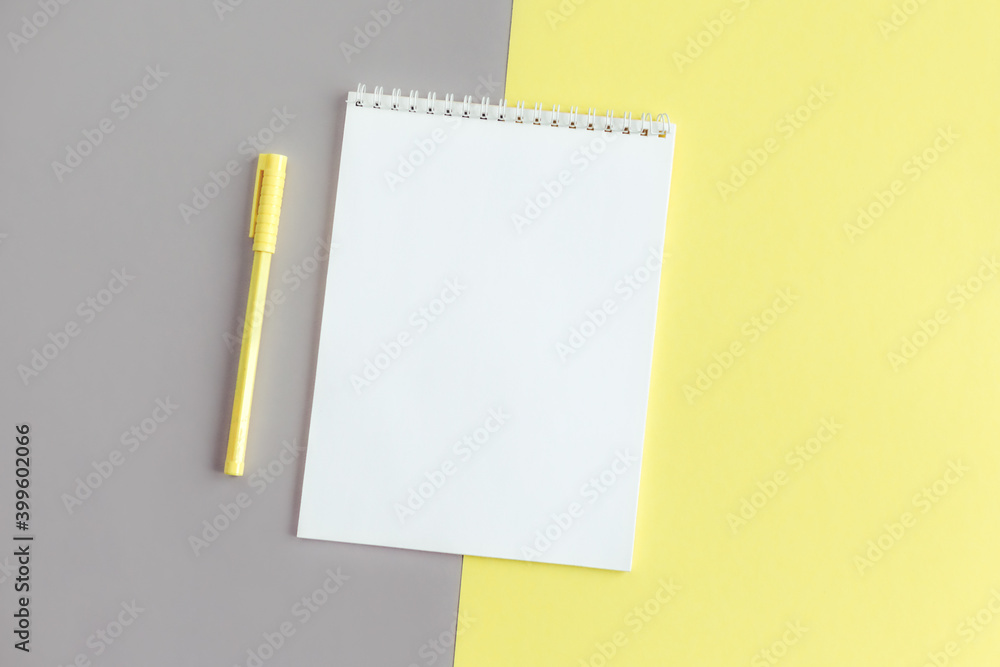Notebook with blank page and pen on a grey and yellow background. Notebook with blank page and pen on a grey and yellow background.
