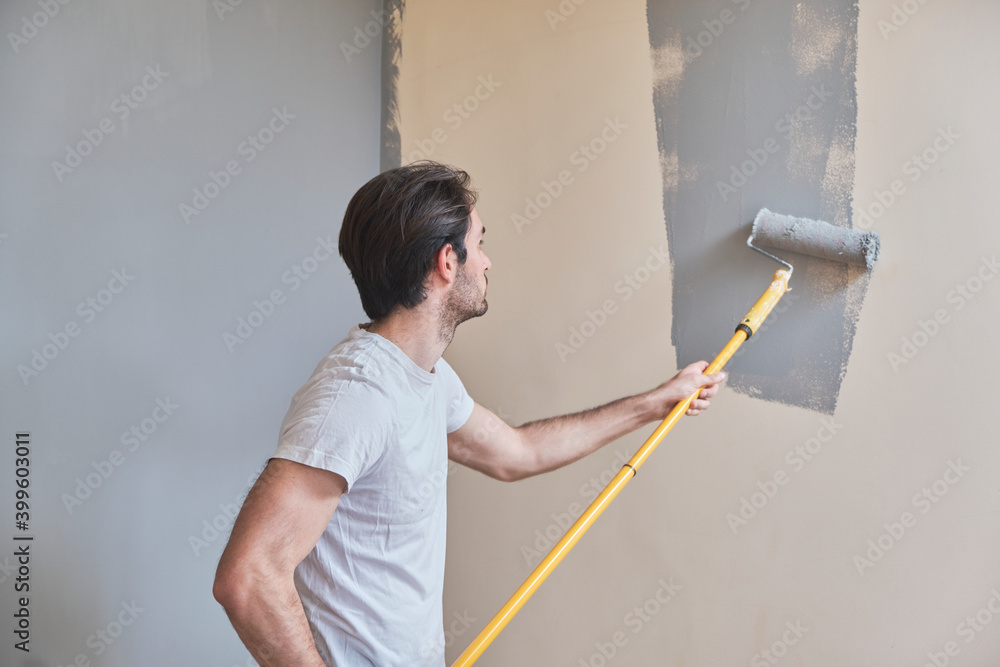 Young handsome man painting his walls Young handsome man painting his walls
