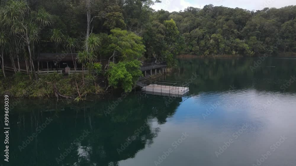 Aerial video showing a popular holiday area on a volcanic crater lake with a pontoon floating by the shore Aerial video showing a popular holiday area on a volcanic crater lake with a pontoon floating by the shore