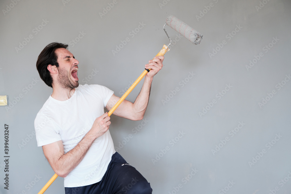 Young handsome man painting his walls