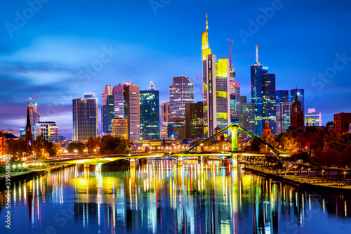 Panoramic view cityscape skyline of business district with skyscrapers and mirror reflections in the river Main during sunset blue hour, Frankfurt am Main. Hessen, Germany