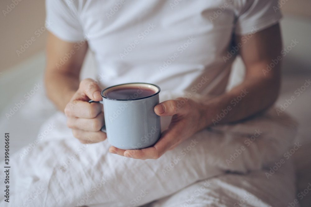 Closeup of man holding cup with tea at the morning in a bed Closeup of man holding cup with tea at the morning in a bed