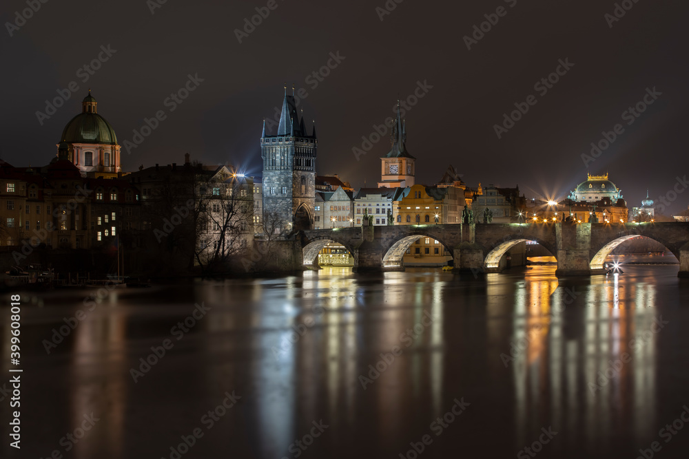 stone illuminated Charles Bridge and bridge tower on the Vltava river in the center of Prague at night and illuminated by street lights
