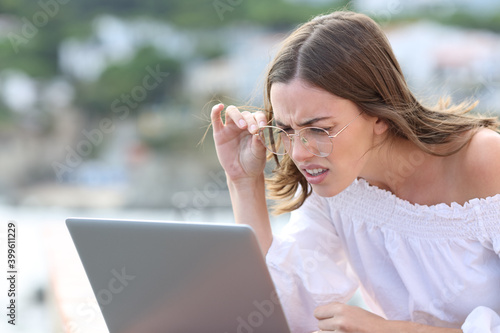 Woman with eyeglasses forcing sight using laptop photo