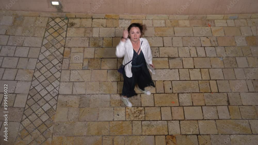 Woman was walking on paved street when hooligans threw balloon with water from balcony down, which exploded when hit ground and splashed in all directions wetting girl. She shakes fist at offenders Woman was walking on paved street when hooligans threw balloon with water from balcony down, which exploded when hit ground and splashed in all directions wetting girl. She shakes fist at offenders
