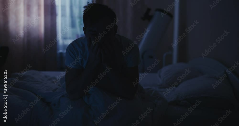 Depressed man in the bed suffers from a symptom insomnia, rubs eyes Depressed man in the bed suffers from a symptom insomnia, rubs eyes