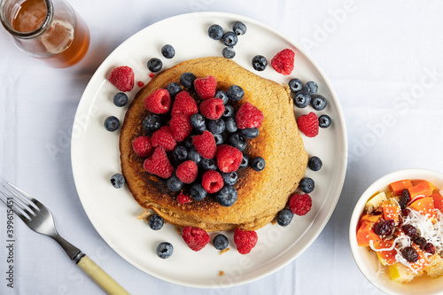 Flat lay view of a homemade vegan dish of hot cakes with raspberries and blueberries in a white surface