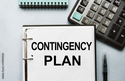 The writing on the notebook has business or marketing content. Top view of work desk, business accessories, calculator. Finance or business concept.