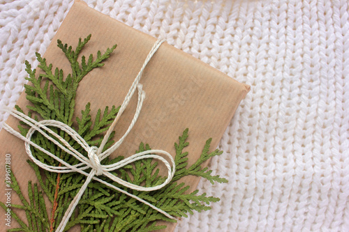 Gift box in craft brown paper decorated with evergreen twig on white background. Eco-friendly Christmas concept. Zero waste presents. Top view, copy space 