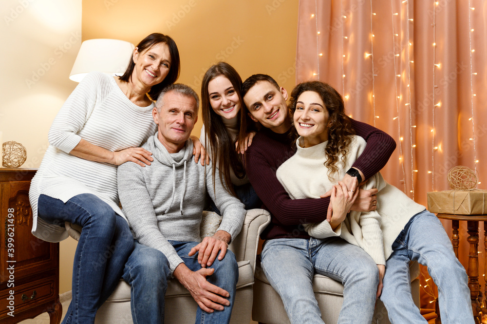 beautiful family is photographed in the New Year's decor while sitting on the couch. home comfort for christmas. new year bulbs. decoration for the new year. grandfather with baushka. children beautiful family is photographed in the New Year's decor while sitting on the couch. home comfort for christmas. new year bulbs. decoration for the new year. grandfather with baushka. children