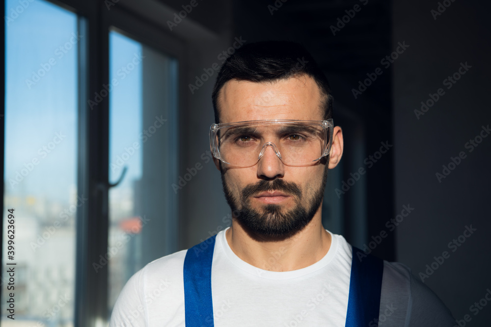 Young worker in blue overalls and plastic safety glasses Young worker in blue overalls and plastic safety glasses
