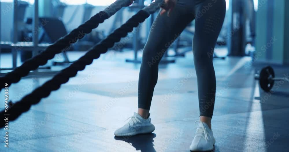 Attractive asian young woman doing intensive training workout with battle ropes determined exercising weightlifting in the gym. Sportswoman. Fitness. Attractive asian young woman doing intensive training workout with battle ropes determined exercising weightlifting in the gym. Sportswoman. Fitness.