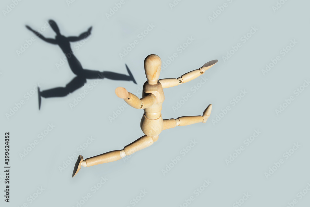 Wooden mannequin happy jump with shadow. Creative happiness concept.