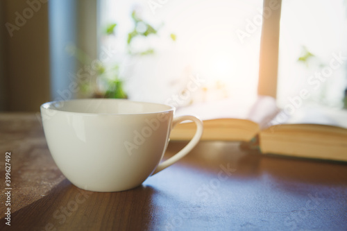 cup of fresh tea or morning coffee and open book at home at morning light, reading book and drinking coffee concept