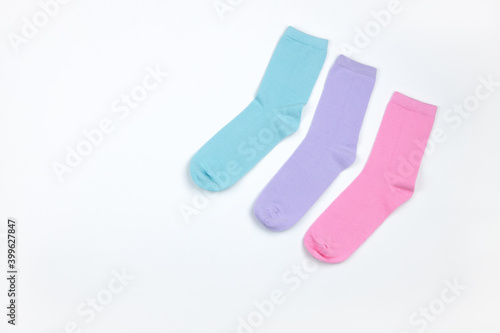 Multicolored children's socks without pattern, laid out in corner of frame, on white background with copy space, flatly, minimal style. Concept children's clothing, housekeeping