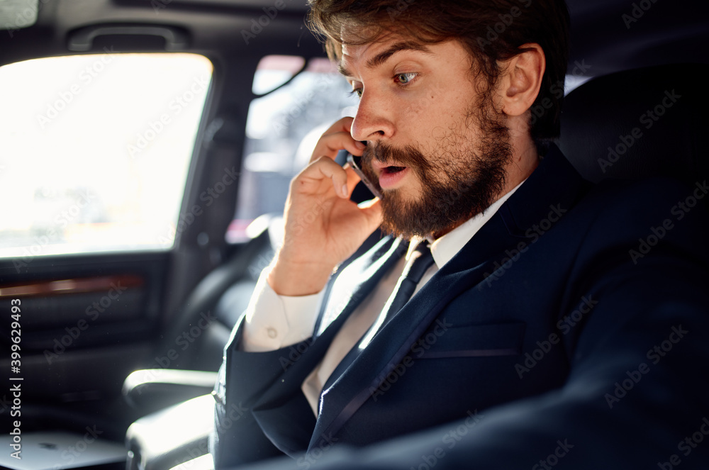 successful rich man in a suit talking on the phone while driving a passenger car successful rich man in a suit talking on the phone while driving a passenger car